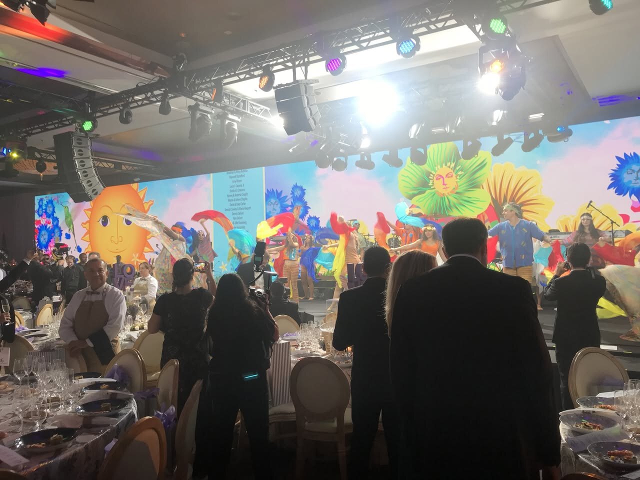 Live performers in front of colorful animated event content at the Make-A-Wish Ball